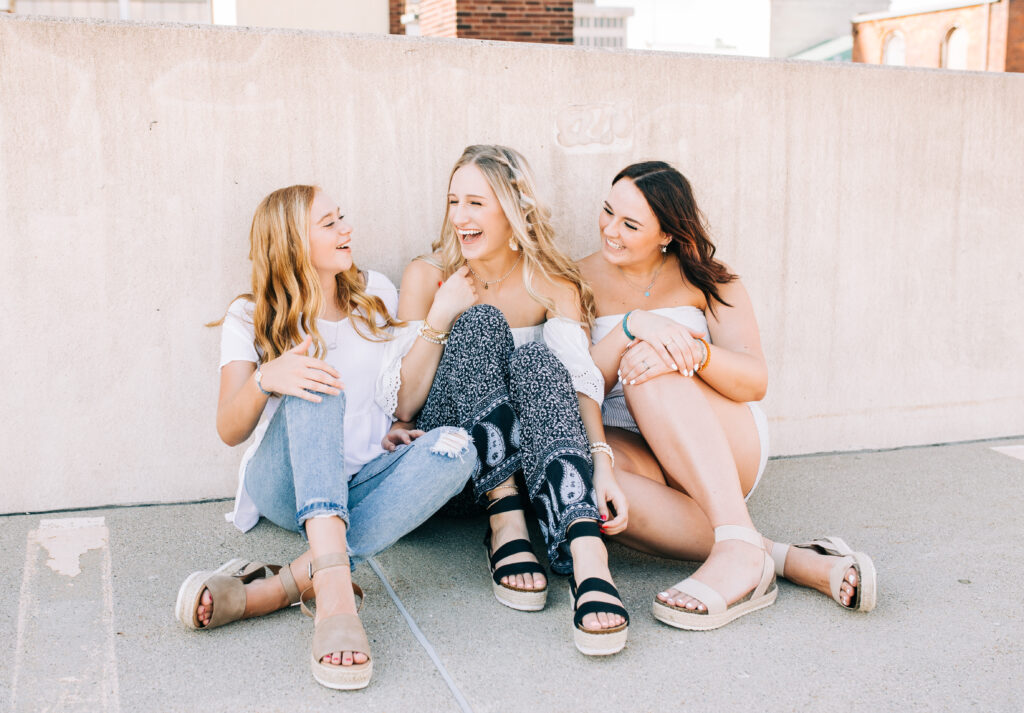 a group of high school senior girls chat and laugh during a fashion photoshoot held in a parking garage in downtown fort wayne