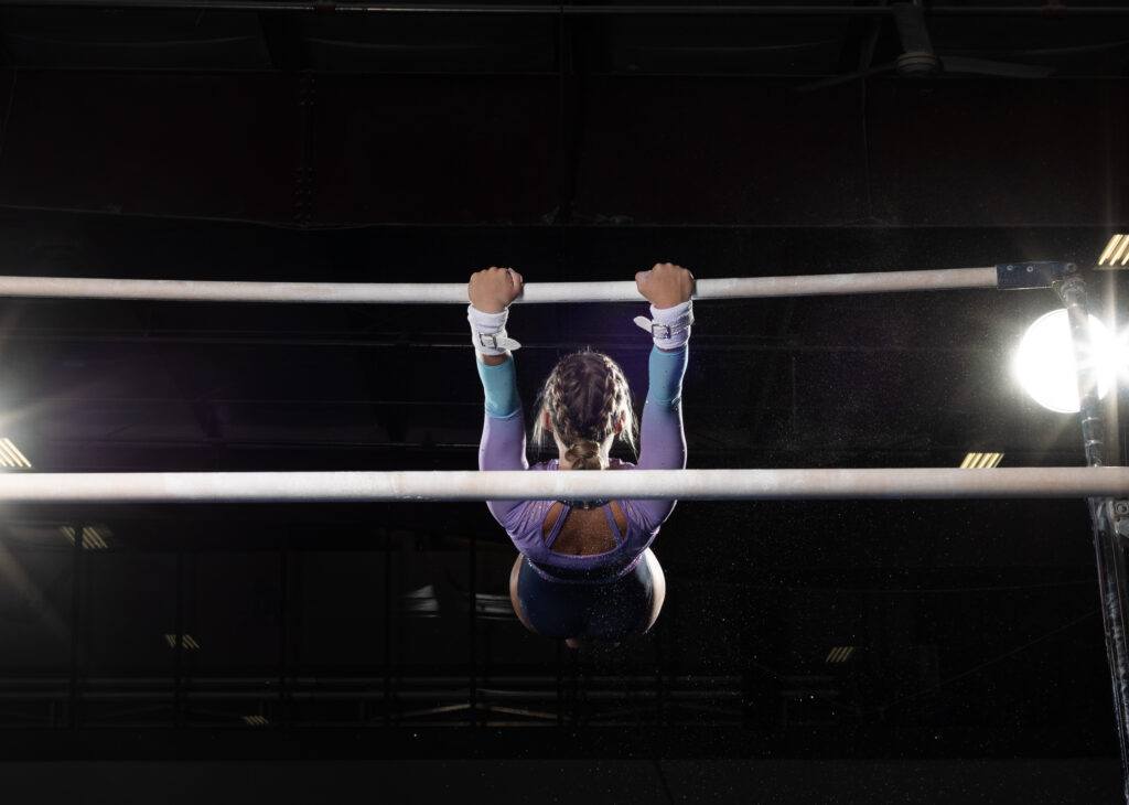 Senior gymnast performing on uneven bars at Summit Academy gym in Fort Wayne, capturing her athleticism and energy."
